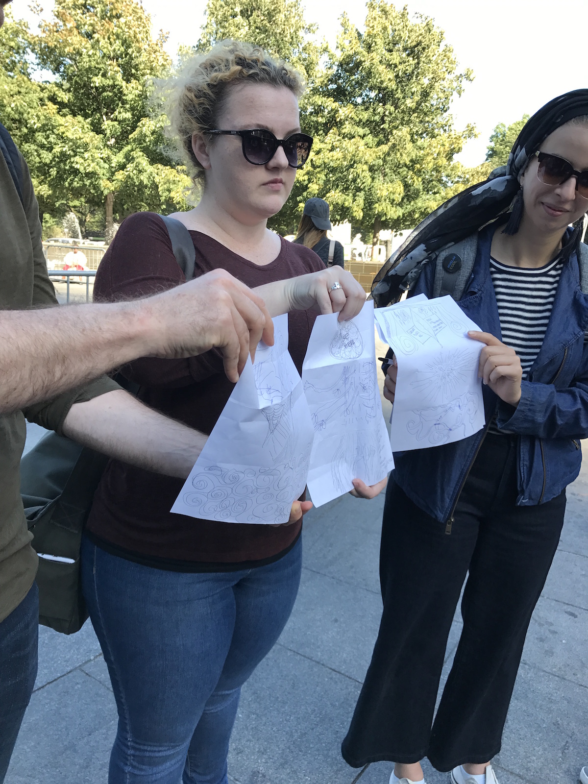 Three Students Show drawings on white paper